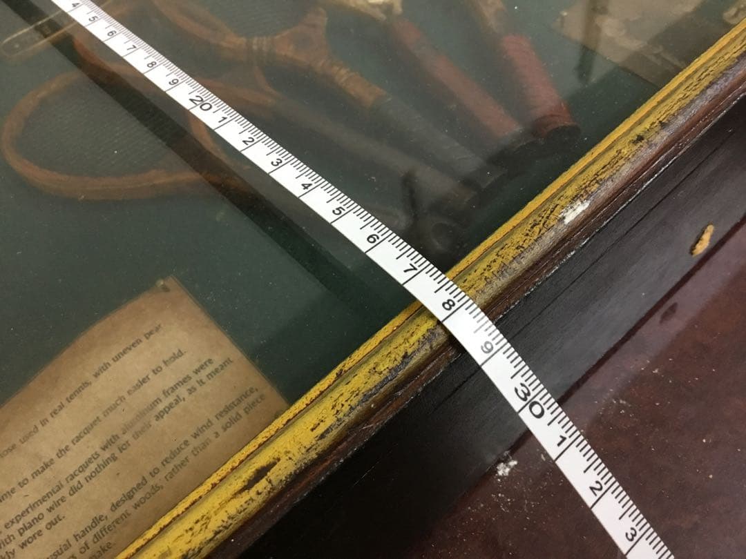 アンティークなテニスラケットの歴史と変遷について解説している彫刻が収められた額装