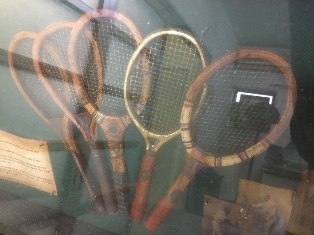 アンティークなテニスラケットの歴史と変遷について解説している彫刻が収められた額装