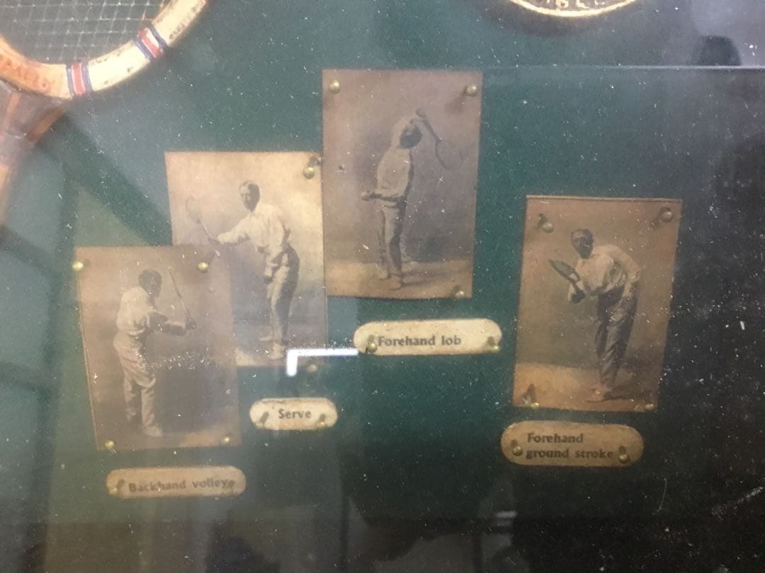 アンティークなテニスラケットの歴史と変遷について解説している彫刻が収められた額装