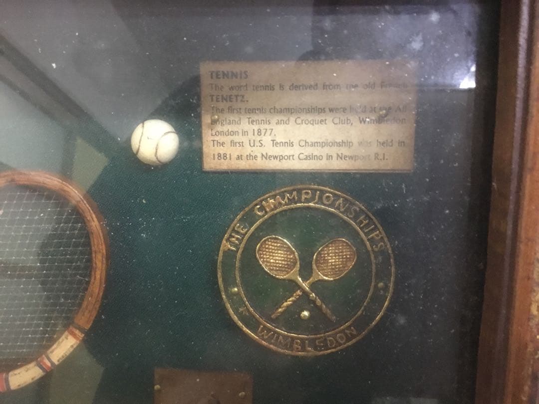 アンティークなテニスラケットの歴史と変遷について解説している彫刻が収められた額装