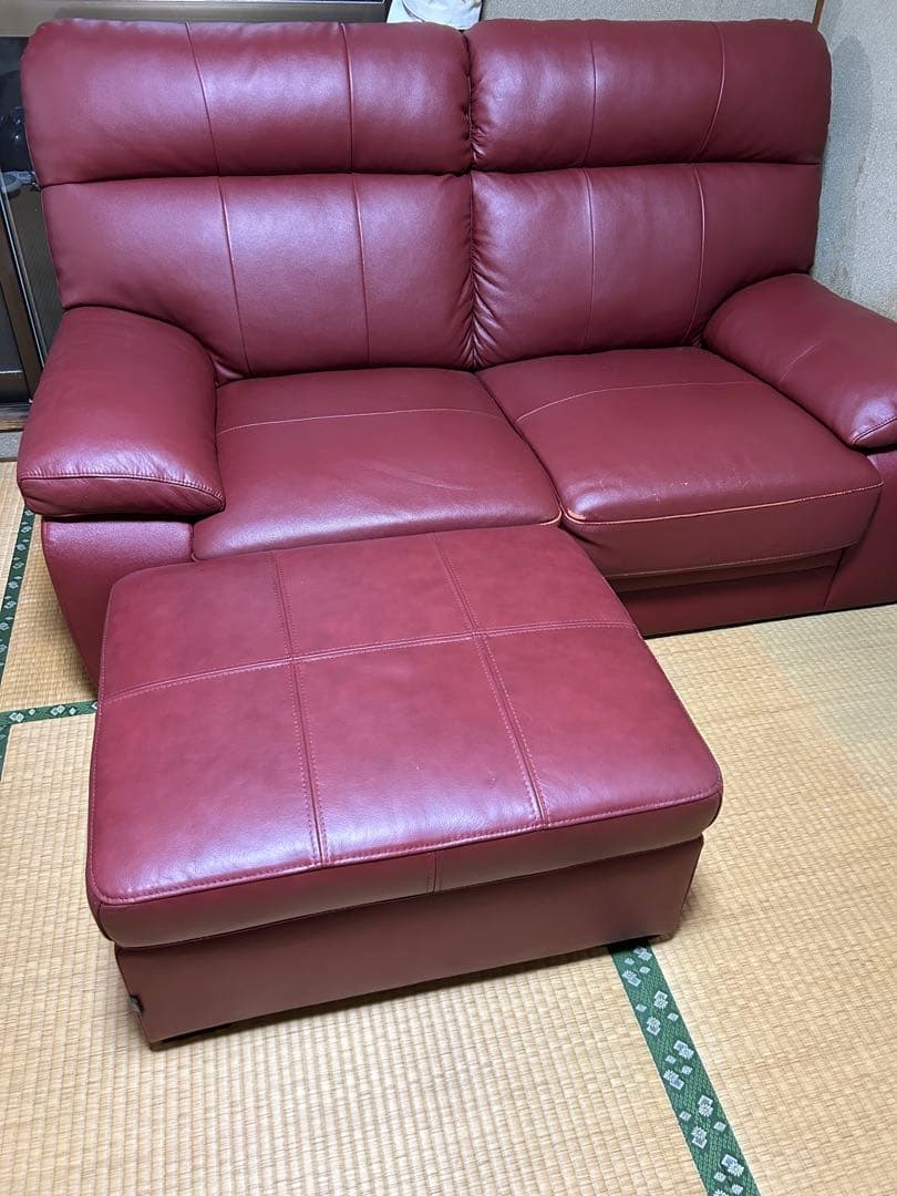 赤い合成皮革の2人掛けソファとオットマン
