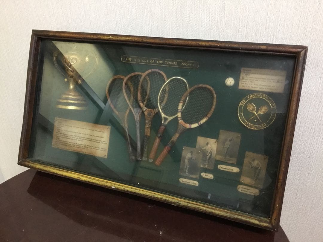 アンティークなテニスラケットの歴史と変遷について解説している彫刻が収められた額装