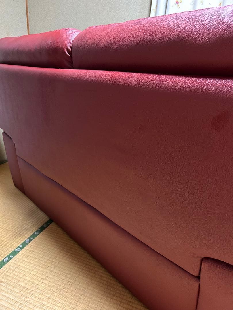 赤い合成皮革の2人掛けソファとオットマン